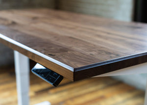 Wooden slab desk with closeup view of remote for electric adjustable base